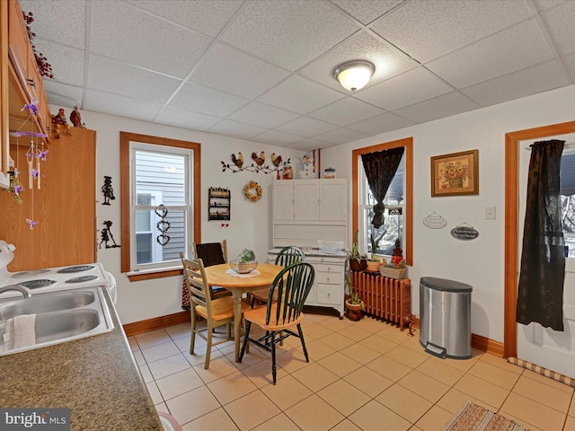 dining area with light tile patterned flooring, sink, and a paneled ceiling