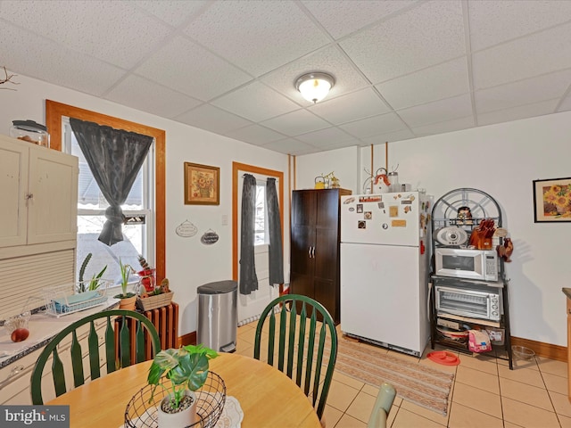 dining space featuring a paneled ceiling and light tile patterned floors