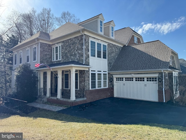 view of side of home with aphalt driveway, a lawn, covered porch, stone siding, and an attached garage