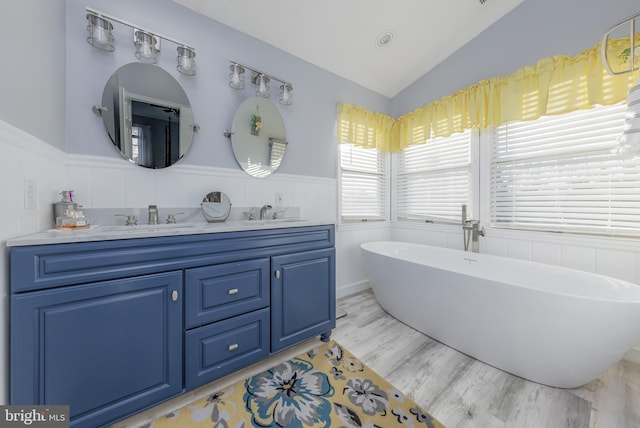 bathroom featuring a washtub, vanity, wood-type flooring, and lofted ceiling