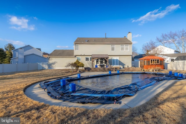 back of property featuring a gazebo, an outdoor structure, and a covered pool