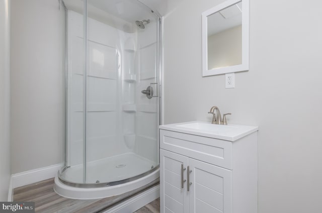 bathroom featuring wood-type flooring, a shower with shower door, and vanity