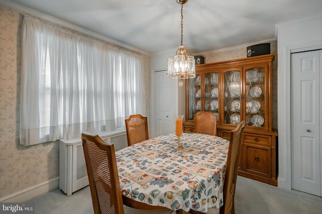 carpeted dining room with ornamental molding, radiator, and a notable chandelier