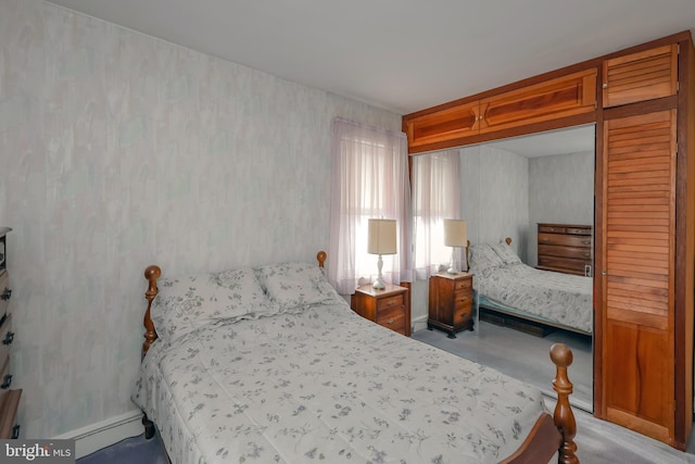 bedroom featuring a baseboard radiator, light carpet, and a closet