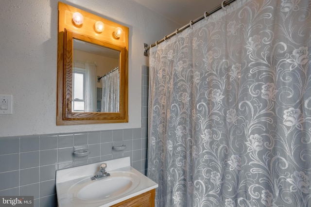 bathroom featuring vanity, a shower with shower curtain, and tile walls