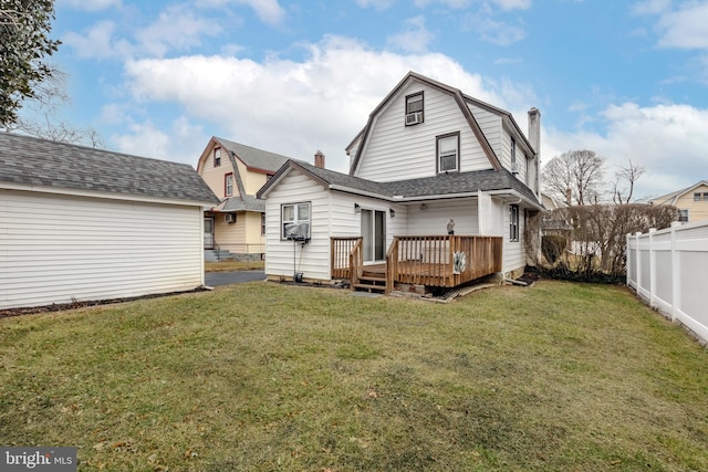 rear view of house with a wooden deck and a lawn