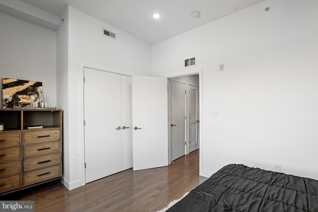 bedroom with dark wood-type flooring and a towering ceiling