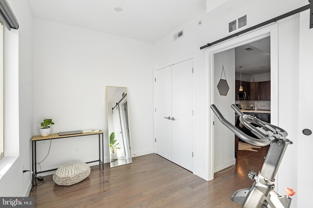 exercise room featuring a barn door and hardwood / wood-style floors