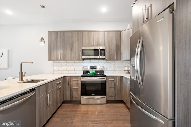 kitchen with sink, decorative light fixtures, dark hardwood / wood-style floors, stainless steel appliances, and decorative backsplash