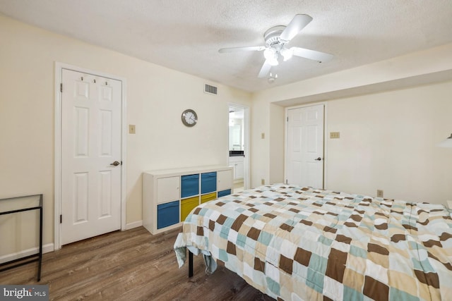 bedroom with ceiling fan, dark hardwood / wood-style floors, and a textured ceiling