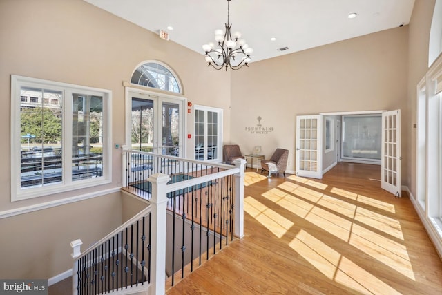 interior space featuring a high ceiling, light hardwood / wood-style flooring, an inviting chandelier, and french doors