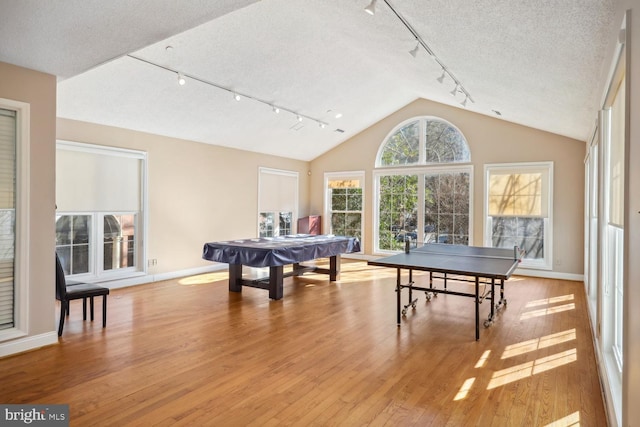 game room featuring vaulted ceiling, light wood-type flooring, pool table, track lighting, and a textured ceiling