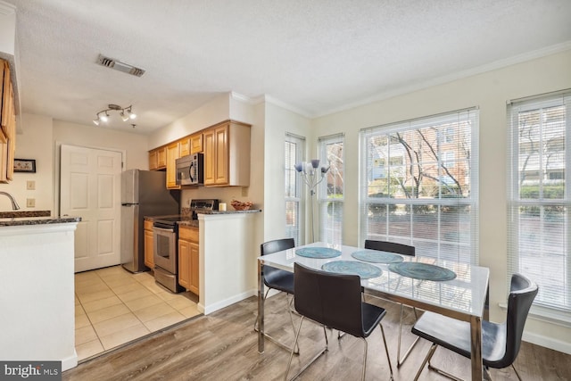 dining room with crown molding, a healthy amount of sunlight, a textured ceiling, and light wood-type flooring