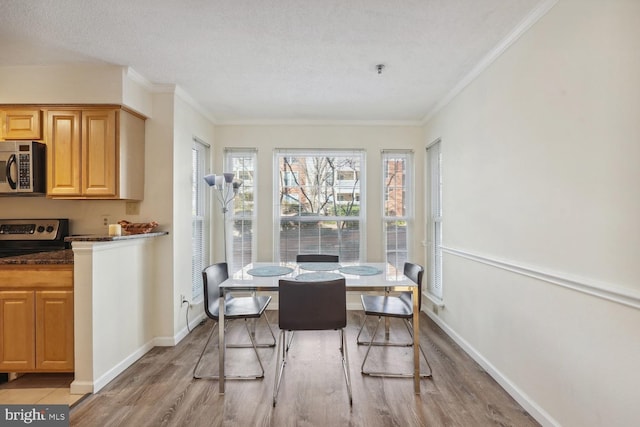 dining area featuring crown molding, light hardwood / wood-style flooring, and a textured ceiling