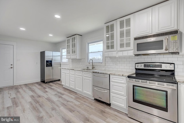 kitchen with appliances with stainless steel finishes, white cabinetry, tasteful backsplash, and sink