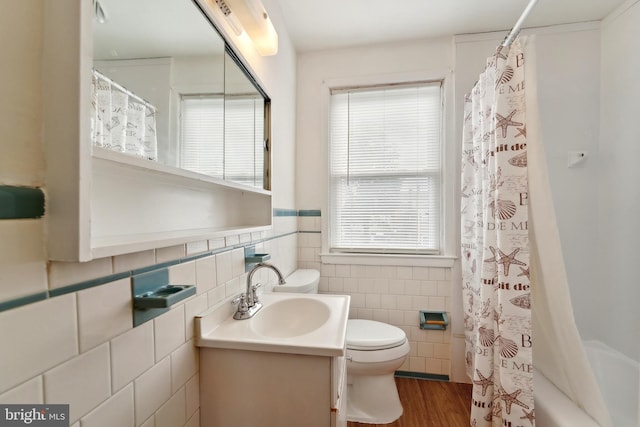 full bathroom with a wainscoted wall, toilet, wood finished floors, tile walls, and vanity