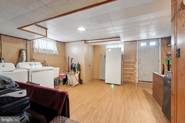 laundry area featuring washing machine and clothes dryer, laundry area, concrete block wall, and wood finished floors