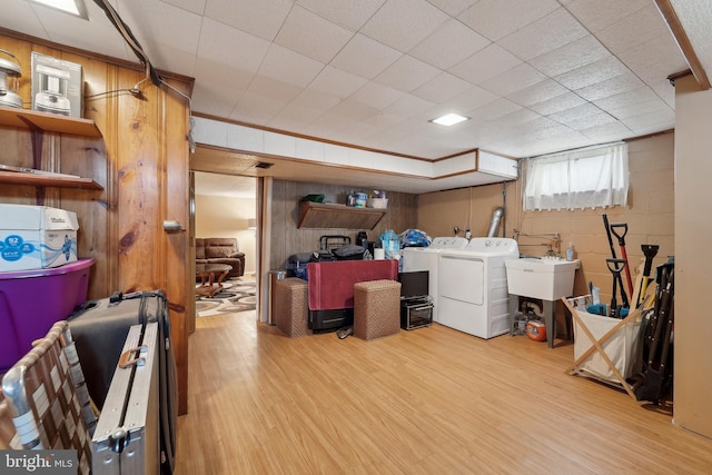 below grade area with crown molding, washer and clothes dryer, wood finished floors, concrete block wall, and a sink