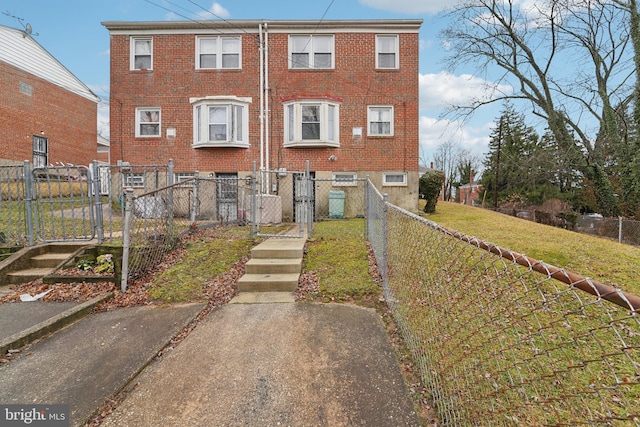 multi unit property with a front lawn, a gate, brick siding, and a fenced front yard