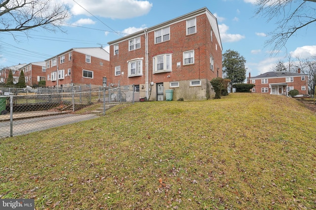 rear view of house with a gate, fence, a yard, a residential view, and brick siding