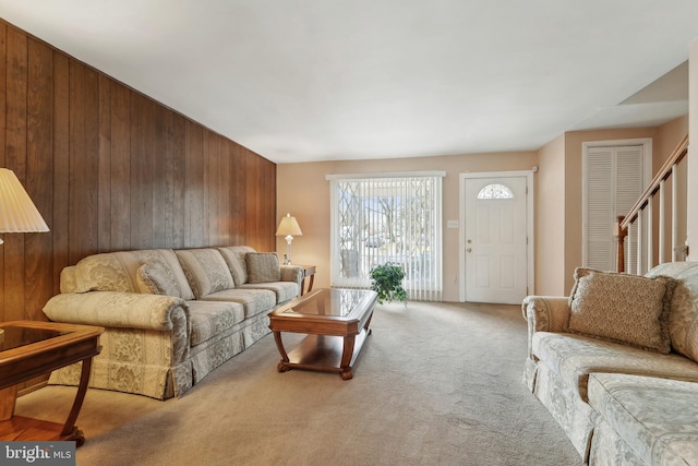 carpeted living room with wood walls