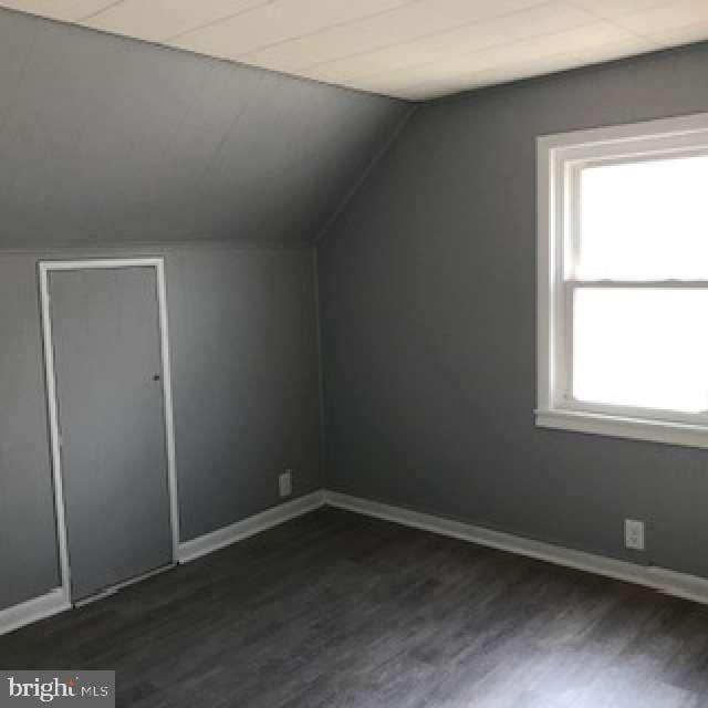 additional living space featuring lofted ceiling and dark hardwood / wood-style floors