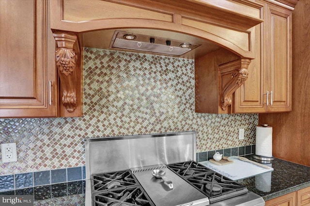 kitchen featuring tasteful backsplash, stainless steel gas range oven, and dark stone counters