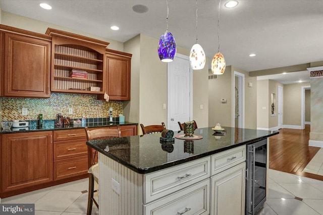 kitchen with light tile patterned flooring, a kitchen breakfast bar, beverage cooler, and a kitchen island