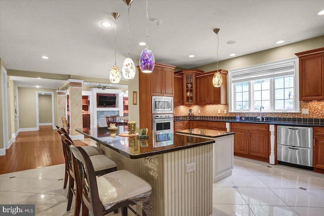 kitchen featuring light tile patterned floors, hanging light fixtures, stainless steel appliances, a center island, and a kitchen breakfast bar