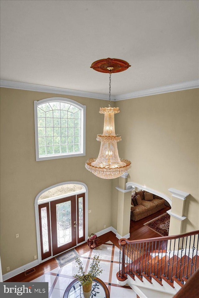 entrance foyer with tile patterned flooring, ornamental molding, and a notable chandelier