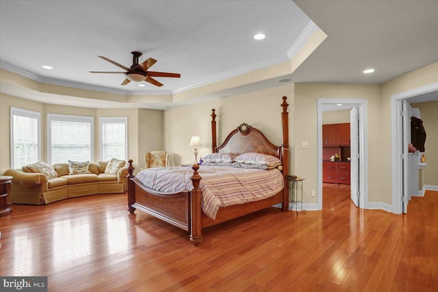 bedroom with a tray ceiling, ornamental molding, ceiling fan, and hardwood / wood-style flooring