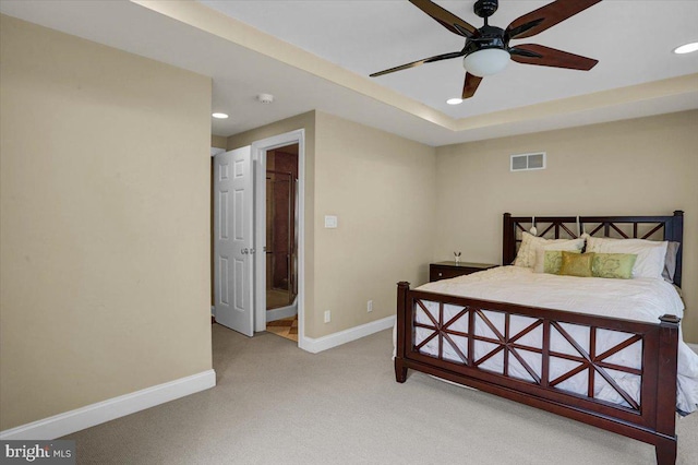 bedroom with a raised ceiling and light carpet