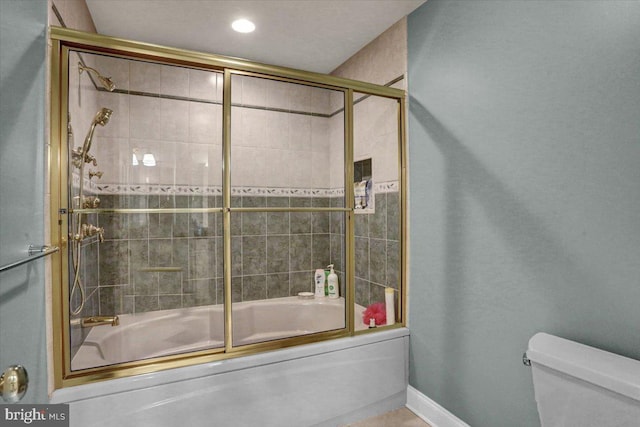 bathroom with toilet and shower / bath combination with glass door