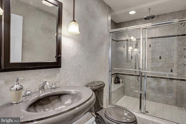 bathroom with sink, a shower with shower door, and toilet