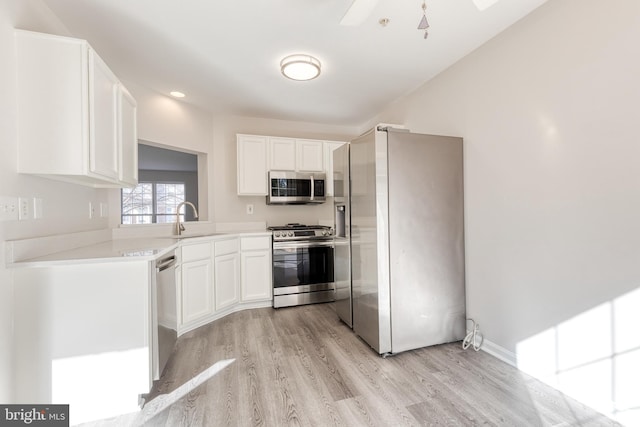 kitchen with sink, stainless steel appliances, white cabinetry, and light hardwood / wood-style floors