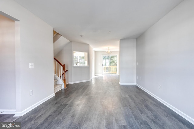 unfurnished living room featuring a chandelier and dark hardwood / wood-style floors