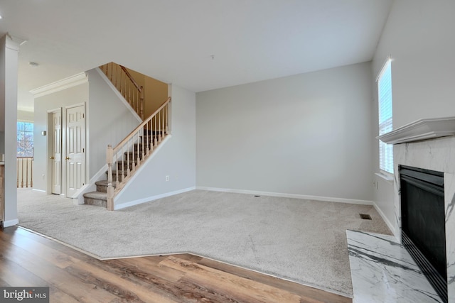 unfurnished living room featuring hardwood / wood-style flooring, a wealth of natural light, and ornamental molding