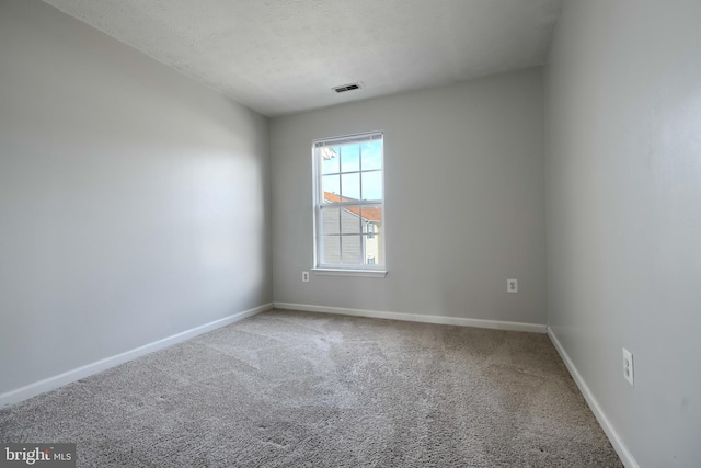 carpeted empty room featuring a textured ceiling