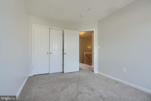 unfurnished bedroom featuring a closet and light colored carpet