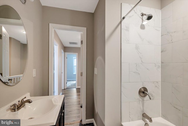 bathroom featuring vanity, hardwood / wood-style floors, and tiled shower / bath combo