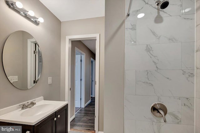 bathroom featuring vanity, wood-type flooring, and a tile shower