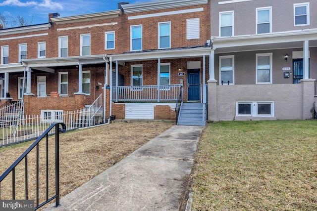 townhome / multi-family property featuring covered porch and a front yard