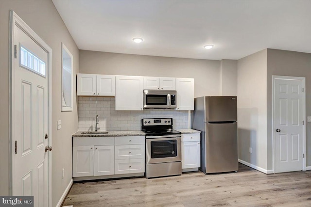 kitchen with sink, appliances with stainless steel finishes, backsplash, light hardwood / wood-style floors, and white cabinets