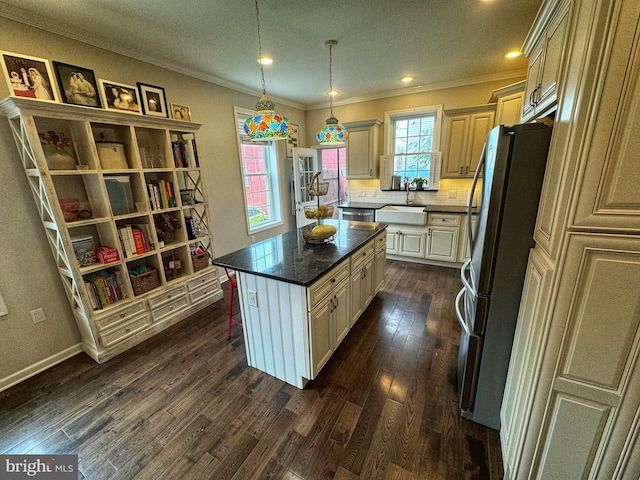 kitchen featuring crown molding, stainless steel refrigerator, a kitchen island, dark hardwood / wood-style flooring, and decorative light fixtures