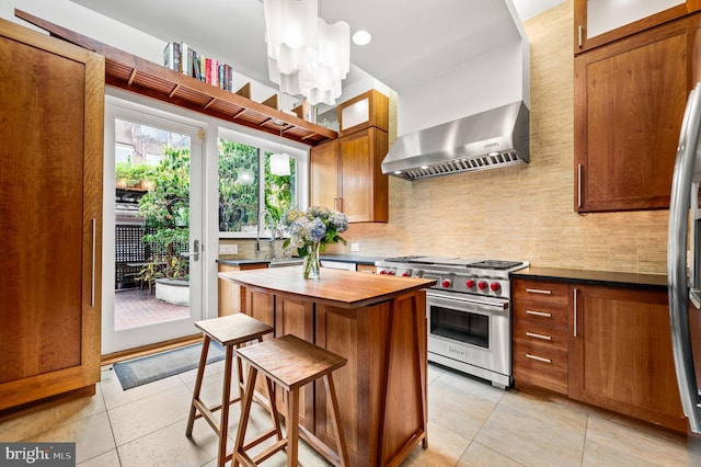 kitchen featuring a breakfast bar area, premium stove, light tile patterned floors, a kitchen island, and wall chimney range hood