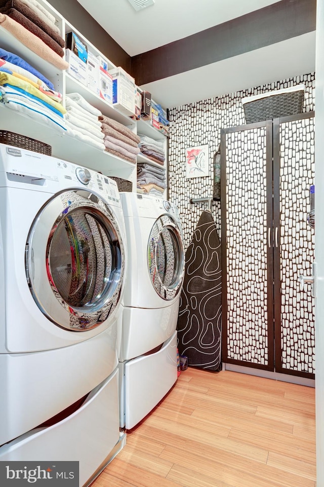 clothes washing area with separate washer and dryer and light hardwood / wood-style flooring