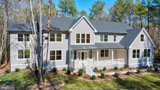 modern farmhouse featuring covered porch, a front lawn, and roof with shingles