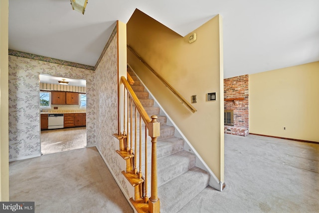 staircase with baseboards, carpet floors, a fireplace, and wallpapered walls