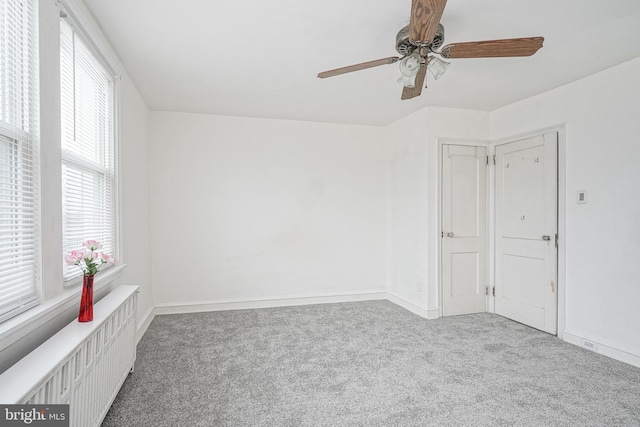 carpeted empty room with ceiling fan and radiator