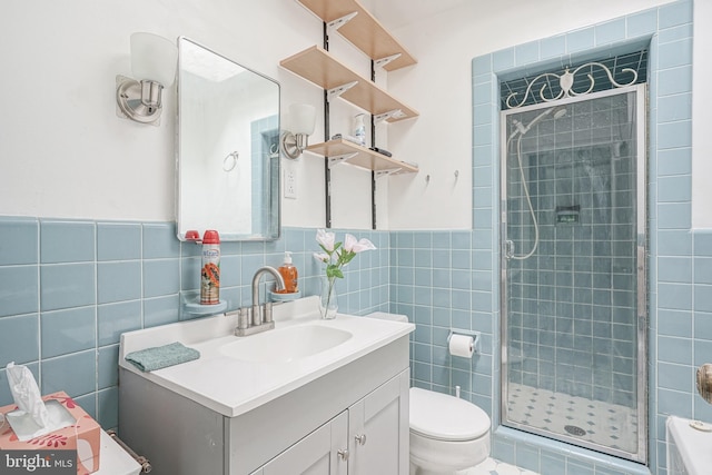 bathroom with vanity, toilet, tile walls, and a shower with shower door